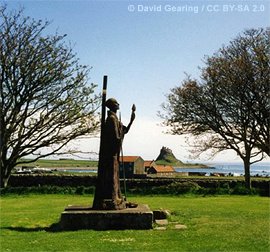 Statue of St. Aidan with Lindisfarne castle in the background