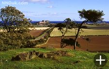 Bamburgh seen from near the road to the north. The Farne Islands are in the distance